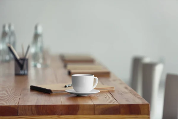 Tavolo con tazza di tè e quaderno preparato per meeting di lavoro in sala conferenze — Foto Stock