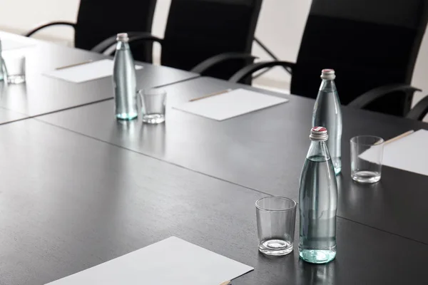 Table with bottles of water prepared for business meeting in conference hall — Stock Photo, Image