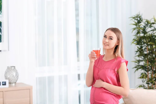 Mulher grávida bonita bebendo suco cítrico em casa — Fotografia de Stock