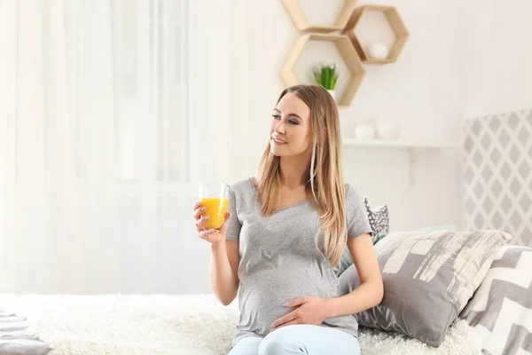 Mulher grávida bonita bebendo suco cítrico em casa — Fotografia de Stock