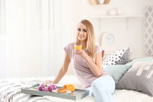 Schöne junge Frau trinkt Zitrussaft, während sie zu Hause frühstückt — Stockfoto