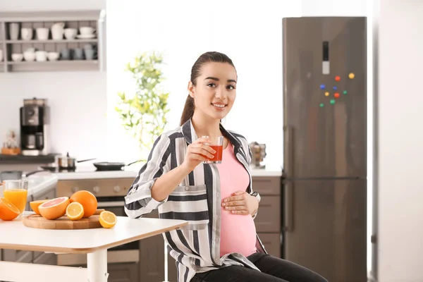 Belle femme enceinte buvant du jus d'agrumes à la maison — Photo