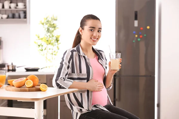 Красива вагітна жінка п'є цитрусовий сік вдома — стокове фото