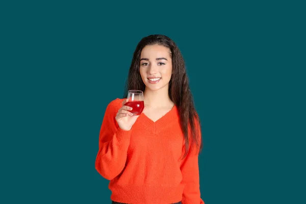 Mooie jonge vrouw met glas sap van citrusvruchten op kleur achtergrond — Stockfoto