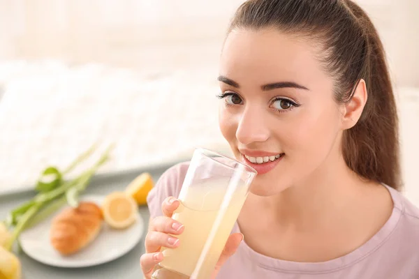 Beautiful young woman drinking citrus juice for breakfast at home — Stock Photo, Image