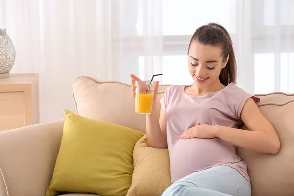 Красивая беременная женщина пьет цитрусовый сок дома — стоковое фото