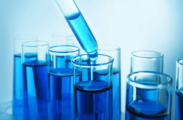 Despejar líquido azul em tubos de ensaio no fundo de cor — Fotografia de Stock