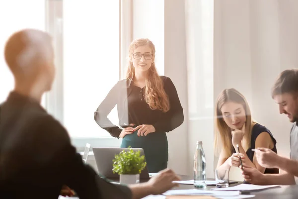 Mujer joven que celebra una reunión de negocios en la oficina, vista a través del vidrio — Foto de Stock