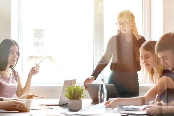 Mujer joven que celebra una reunión de negocios en la oficina, vista a través del vidrio — Foto de Stock