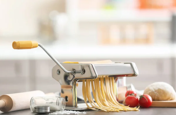 Making tagliatelle with pasta machine on table in kitchen — Stock Photo, Image
