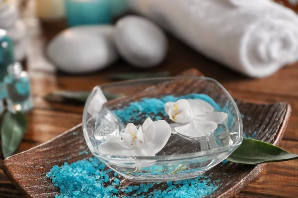 Glass bowl of water with flowers and sea salt for spa treatment on tray — Stock Photo, Image