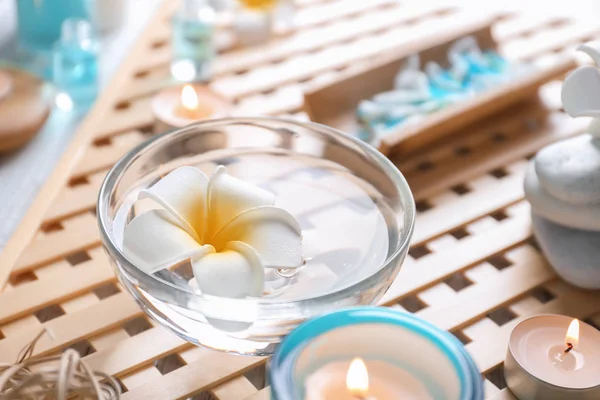 Стеклянная чаша с плавающим цветком в воде на столе — стоковое фото