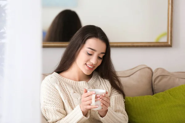 Mooie jonge vrouw met kop hete thee thuis — Stockfoto