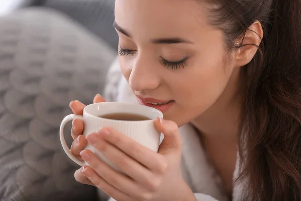 美丽的年轻女子与杯热茶在家里, 特写 — 图库照片
