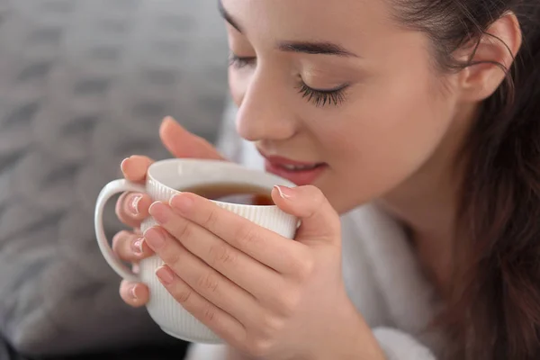 Beautiful young woman with cup of hot tea at home, closeup — Stock Photo, Image