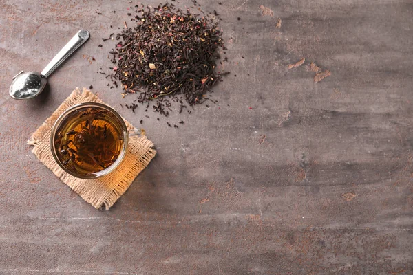 Composição de leigos planos com folhas de chá secas e bebida quente no fundo cinza — Fotografia de Stock