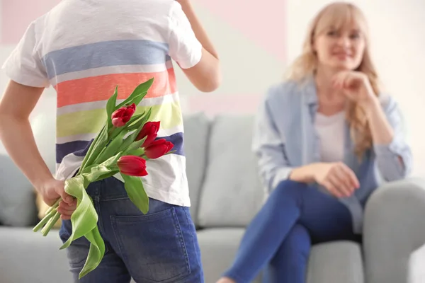 Little boy hiding tulip bouquet for mother behind his back at home — Stock Photo, Image
