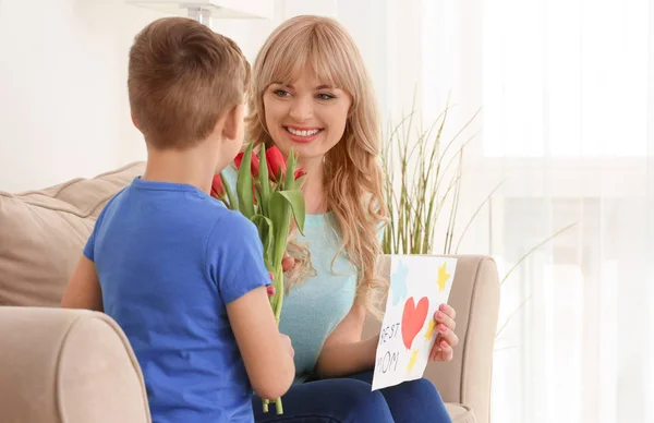 Cute little boy congratulating his mother at home — Stock Photo, Image