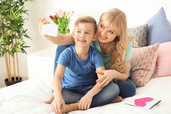 Young woman taking selfie with her son in bedroom — Stock Photo, Image