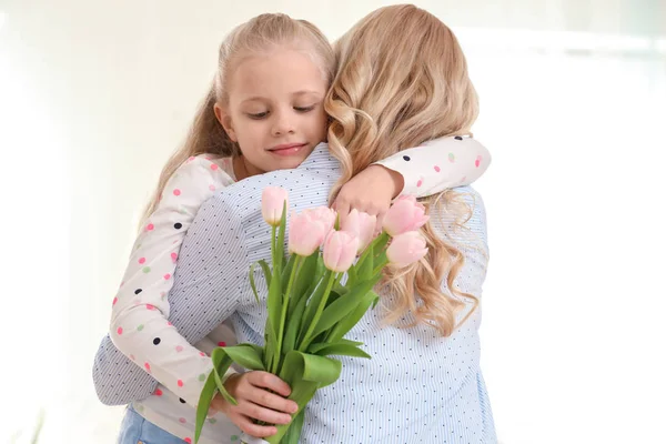 Retrato de linda niña y su madre con ramo de tulipanes sobre fondo claro —  Fotos de Stock