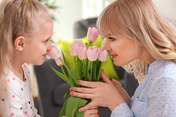 Ritratto di bambina carina e sua madre con bouquet di tulipani a casa — Foto Stock