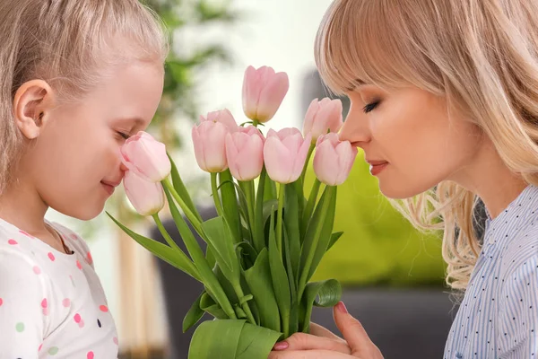 Portrait of cute little girl and her mother with tulip bouquet at home — Stock Photo, Image