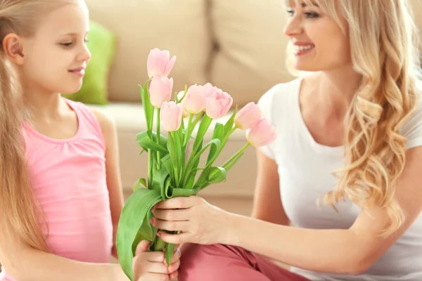 Cute little girl giving tulip bouquet to her mother at home — Stock Photo, Image