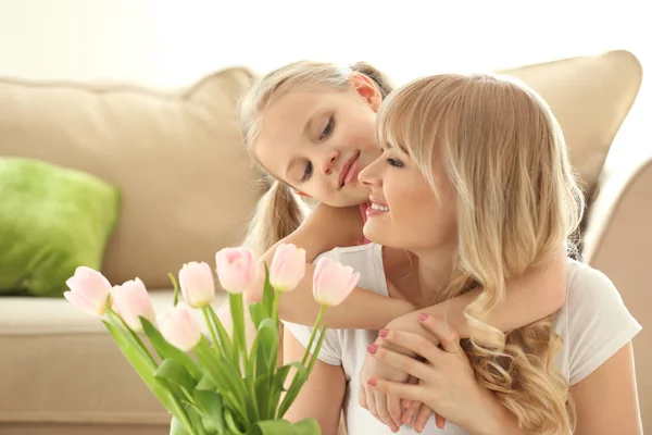 Ritratto di bambina carina e sua madre con bouquet di tulipani a casa — Foto Stock