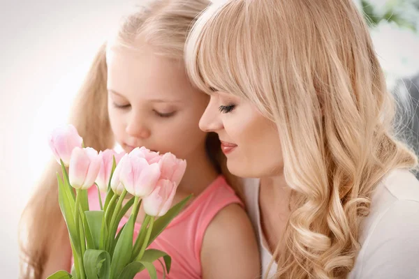 Ritratto di bambina carina e sua madre con bouquet di tulipani su sfondo chiaro — Foto Stock