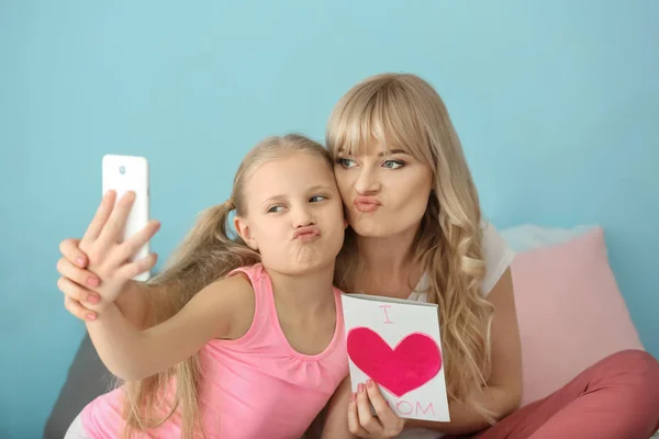 Cute little girl and her mother taking selfie with handmade card at home — Stock Photo, Image