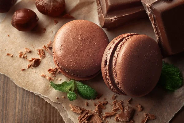 Macarons savoureux, chocolat et noisettes sur fond de bois — Photo