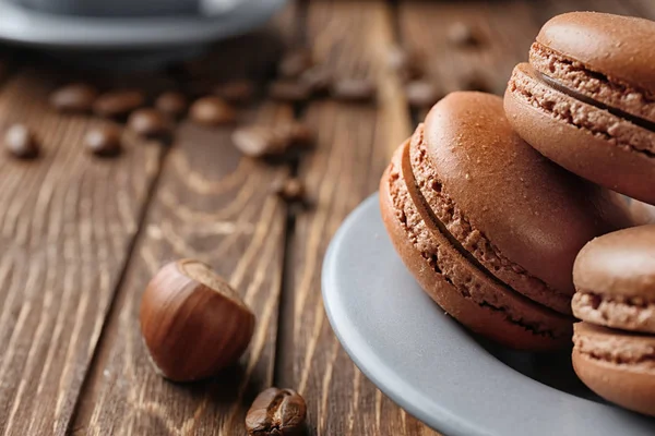 Plate with delicious chocolate macarons on wooden table — Stock Photo, Image
