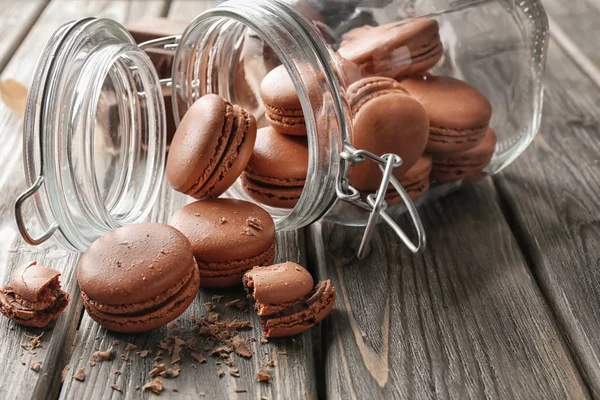 Glass jar and delicious chocolate macarons on table — Stock Photo, Image