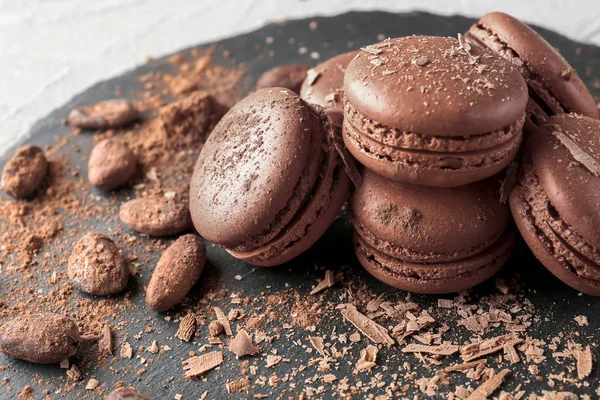 Slate plate with delicious chocolate macarons and cocoa beans, closeup — Stock Photo, Image