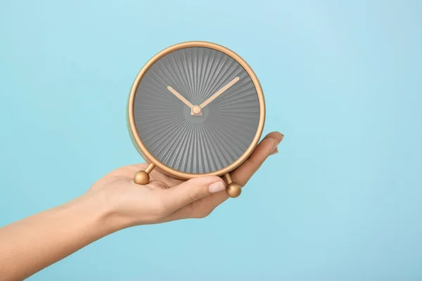 Kvinna som håller väckarklocka på färgbakgrund. Time management koncept — Stockfoto