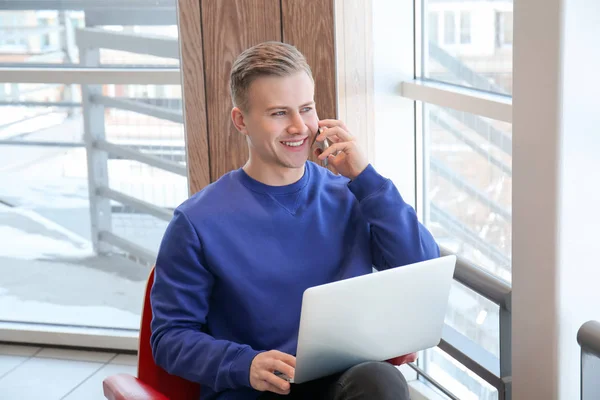 Νέος ελεύθερος επαγγελματίας μιλάμε στο κινητό τηλέφωνο, ενώ συνεργάζεται με το laptop στο café — Φωτογραφία Αρχείου