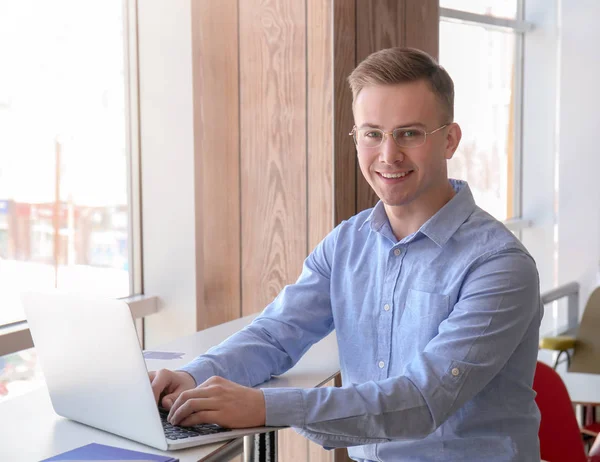 Young freelancer working with laptop at table in cafe — Stock Photo, Image