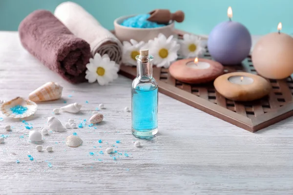 Bottle with blue liquid and blurred spa accessories on background — Stock Photo, Image
