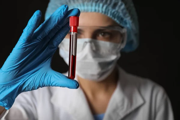 Lab worker holding test tube with blood sample on black background — Stock Photo, Image