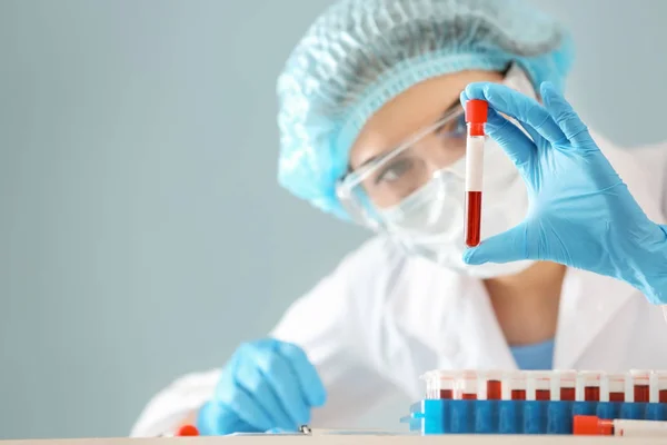 Femme tenant un tube à essai avec échantillon de sang en laboratoire — Photo