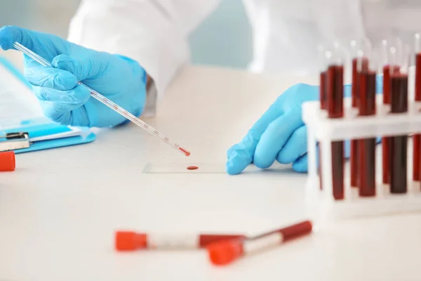 Mujer que trabaja con muestras de sangre del tubo de ensayo en la mesa — Foto de Stock