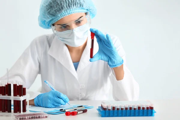 Woman working with blood sample in test tube at table — Stock Photo, Image