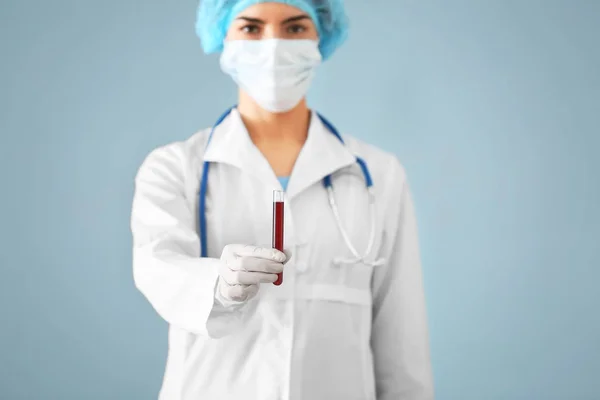 Labb arbetstagaren innehar provrör med blodprov på färgbakgrund — Stockfoto