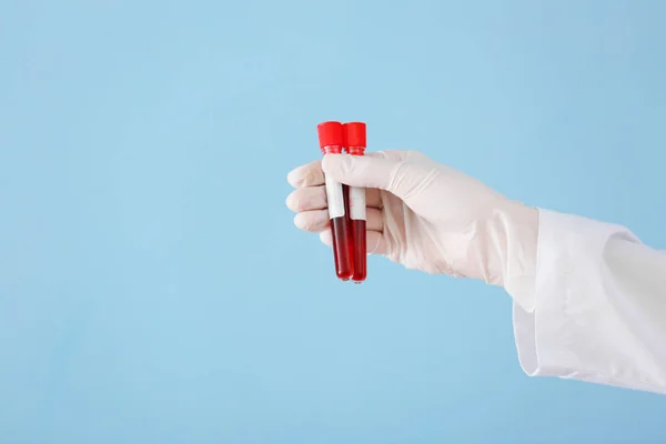 Lab worker holding test tubes with blood samples on color background — Stock Photo, Image