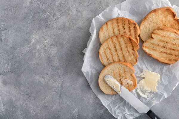 Pão torrado saboroso com manteiga no fundo cinza, vista superior — Fotografia de Stock