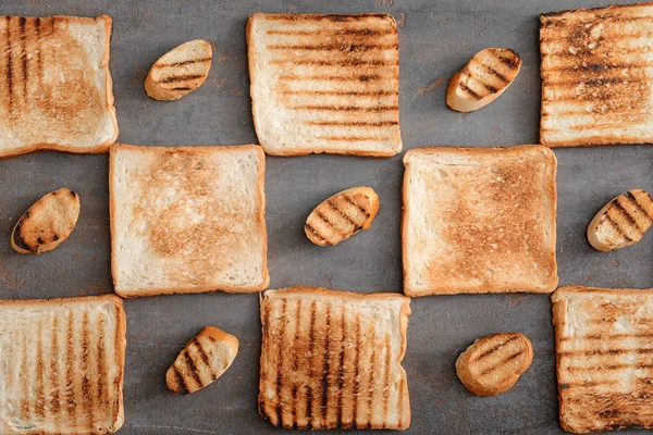 Επίπεδη lay σύνθεση με νόστιμο φρυγανισμένο ψωμί σε γκρίζο φόντο — Φωτογραφία Αρχείου