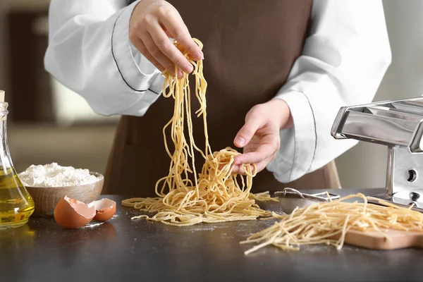 Köchin bereitet Pasta am Tisch zu — Stockfoto