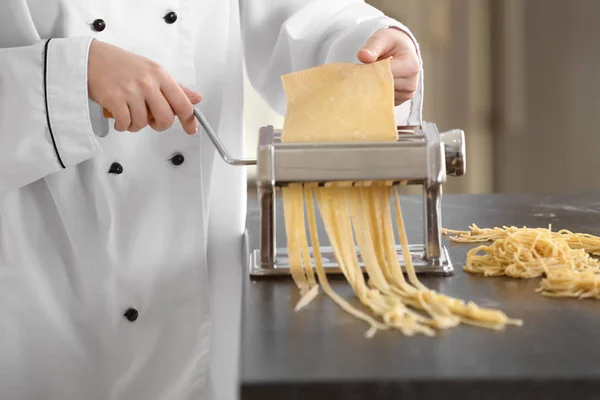 Vrouwelijke chef-kok noedels met Pastamachine aan tafel maken — Stockfoto