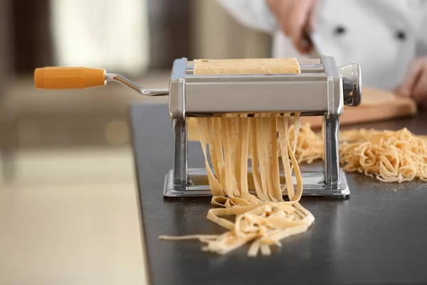 Pasta maker with dough and blurred chef on background — Stock Photo, Image