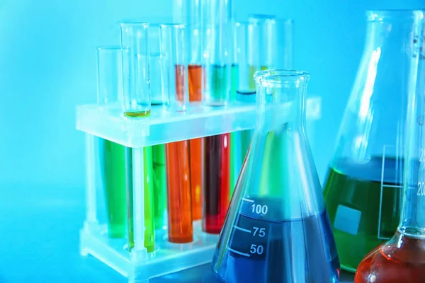 Verrerie chimique avec des échantillons colorés sur fond de couleur — Photo